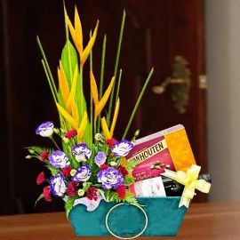 A Bottle of Red Wine with Chocolates and Flower Arrangement in a basket